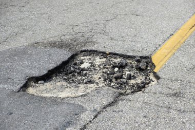 Amerikan karayolu yüzeyinde derin çukurlu asfalt yolda hasar var. Acilen onarılması gereken harap olmuş bir yol..