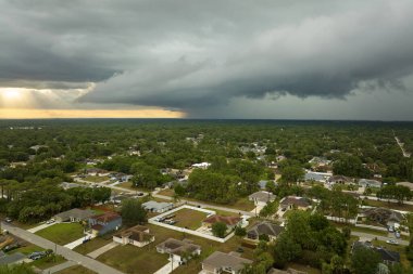 Dark stormy clouds forming on gloomy sky before heavy rainfall over suburban town area.