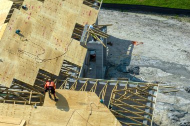 Florida kırsal kesiminde ahşap iskeleti olan bitmemiş bir banliyö evinin çatı inşaatında çalışan profesyonel müteahhitler. Amerika 'da konut geliştirme kavramı.