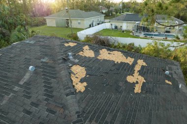 Tamire ihtiyacı olan harap bir çatı. Florida 'daki Ian kasırgasından sonra asfalt kiremitleri kaybolan rüzgârlı ev çatısı..