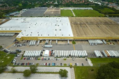 Devasa lojistik merkezinin en üst görüntüsü. Ticari karavan kamyonları daha fazla sevkiyat için perakende ürün indiriyor ve yüklüyor. Küresel ekonomi kavramı.