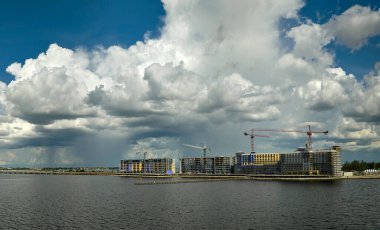 Deniz kıyısındaki yüksek konutlu apartman şantiyesinde vinç kaldırma. Gayrimenkul geliştirme.