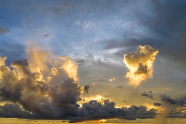 White fluffy cumulonimbus clouds forming before thunderstorm on evening sky. Changing stormy cloudscape weather at sunset.