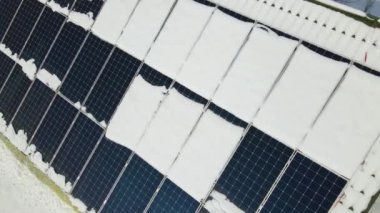 Aerial view of house roof with solar panels covered with snow melting down in winter end for producing clean energy. Concept of low effectivity of renewable electricity in northern region.