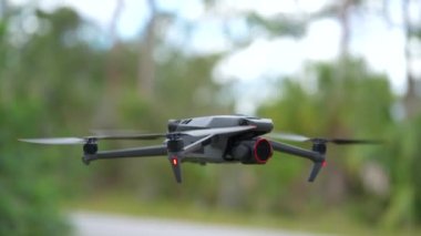 Drone quadcopter with digital camera and fast rotating propellers flying taking video and pictures.