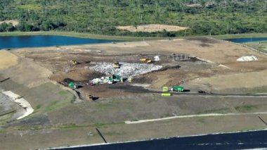 Yerin altına büyük miktarda çöp gömen buldozer traktörleriyle dolu bir çöp sahası. Açık atık yönetiminin çevre üzerindeki zararlı etkisi.