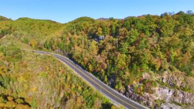 Wide highway road in North Carolina leading through Appalachian mountains with yellow fall forest and fast moving traffic. Scenic route in US national park area.