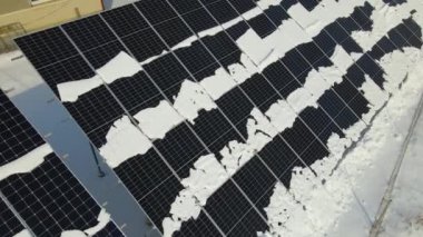 Aerial view of snow melting from covered solar photovoltaic panels at sustainable electric power plant for producing clean electrical energy. Low effectivity of renewable electricity in winter.