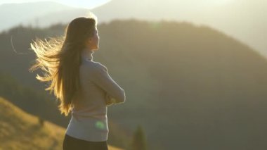 Yürüyüş yapan kadın dağ yolunda duruyor ve vahşi doğa yolculuğunda akşam doğasının tadını çıkarıyor. Yüksek tepe yolundan geçen yalnız bir kadın gezgin. Sağlıklı yaşam tarzı kavramı.