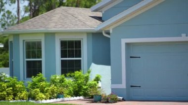Konut kavramı. Florida 'daki tipik modern Amerikan özel evi çatısı asfalt kiremitlerle, geniş garaj kapısı ve bahçedeki yeşil çimlerle kaplı..