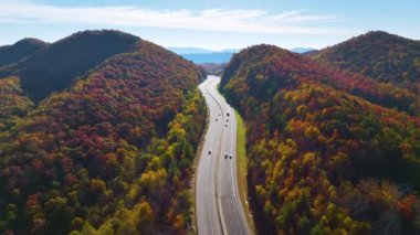 I-40 freeway road leading to Asheville in North Carolina thru Appalachian mountains with yellow fall forest and fast moving trucks and cars. Concept of high speed interstate transportation.