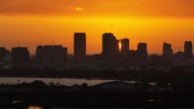 Gün batımında Tampa şehrinin şehir merkezindeki yüksek gökdelen binalarından kalkan yolcu uçağının yukarıdan görüntüsü. Ticari finans bölgesiyle Amerikan megapolis.