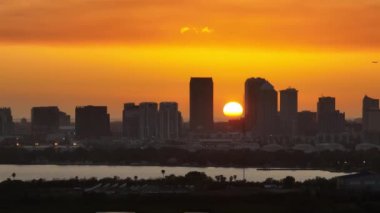 Gün batımında Tampa şehrinin şehir merkezinden kalkan yolcu uçağının hava görüntüsü. Modern Amerikan şehir merkezindeki yüksek gökdelen ofis binalarının karanlık silueti..