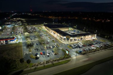 Otoparkta park yerleri ve yönler için çizgiler ve işaretlerle park edilmiş birçok arabanın gece görüşü. Bir alışveriş merkezinin önünde araçlar için yer.