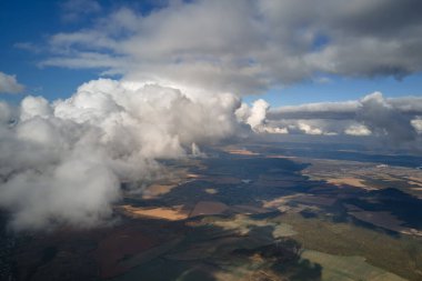 Dünya 'nın yüksek irtifasındaki uçak penceresinden hava manzarası beyaz kabarık kümülüs bulutlarıyla kaplı..
