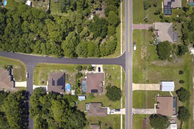 Aerial view of american small town in Florida with private homes between green palm trees and suburban streets in quiet residential area.