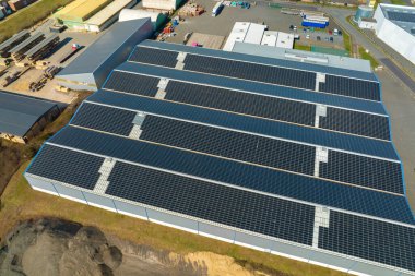 Sanayi binasının çatısına yeşil ekolojik elektrik üretmek için monte edilen mavi fotovoltaik güneş panellerinin hava görüntüsü. Sürdürülebilir enerji konsepti üretimi.