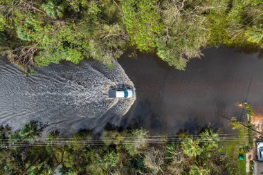 Hurricane Ian flooded street with moving cars and surrounded with water houses in Florida residential area. Consequences of natural disaster. clipart