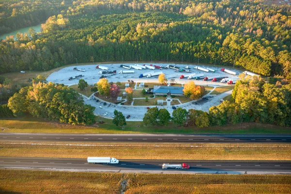 Top view of large rest area near busy multilane american freeway with fast moving cars and trucks. Recreational resting place during interstate traveling.