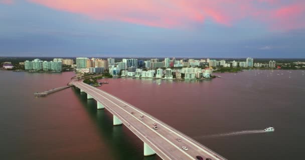 フロリダ州サラソータ市は ウォーターフロントオフィスの高層ビルとジョン リング コーズウェイがダウンタウンからセント アーマンド キーに至る日没 米国における住宅 交通の開発 — ストック動画