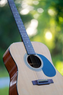 Acoustic guitar outdoors on greenery background. Concept of calm music.