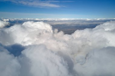 Dünya 'nın yüksek irtifasında, yağmur fırtınasından önce oluşan kabarık kümülüs bulutlarıyla kaplı uçak penceresinden hava görüntüsü.