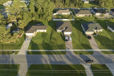 Aerial view of american small town in Florida with private homes between green palm trees and suburban streets in quiet residential area.