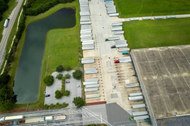 Devasa lojistik merkezinin en üst görüntüsü. Ticari karavan kamyonları daha fazla sevkiyat için perakende ürün indiriyor ve yüklüyor. Küresel ekonomi kavramı.