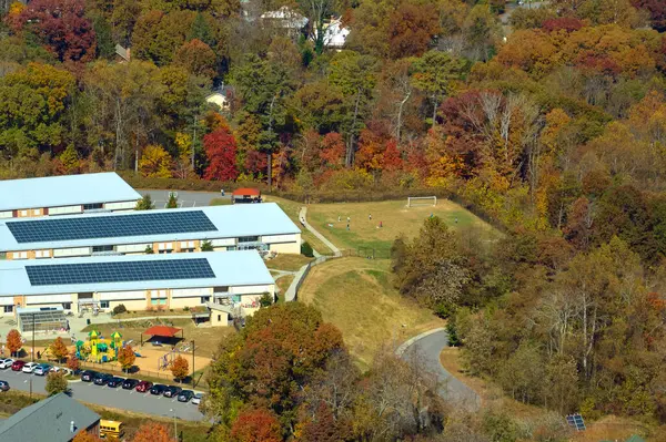 Roof of american school building covered with photovoltaic solar panels for production of electric energy. Renewable energy concept.