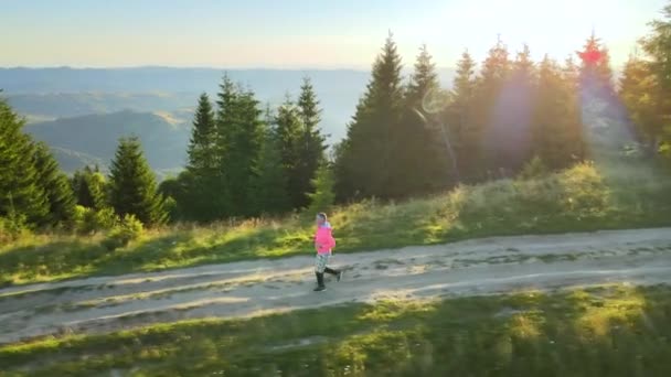 カラフルな日の出に登山トレイルのジョギングトレーニング ハイランドの汚れた道を一人で走る男 — ストック動画
