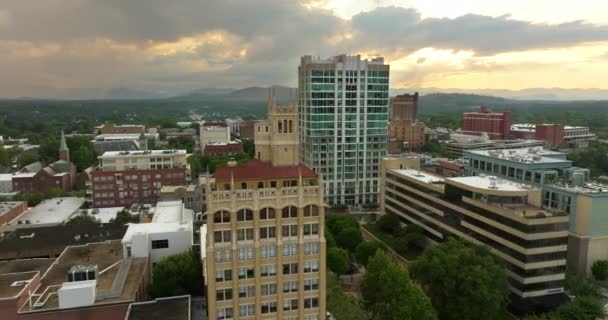 ノースカロライナ州アパラチアンの都市アシュビルを望むパノラマの景色は ダウンタウンの建築とブルーリッジマウンテンヒルが日没の距離にあります 米国の旅行先 — ストック動画