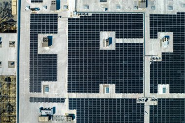 Sanayi binasının çatısına yeşil ekolojik elektrik üretmek için monte edilen mavi fotovoltaik güneş panellerinin hava görüntüsü. Sürdürülebilir enerji konsepti üretimi.