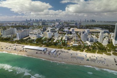 Sıcak Florida güneşinde dinlenen turistlerle birlikte güney sahilinin kumlu yüzeyi. Yüksek lüks otelleri ve apartmanları olan Miami Beach City. Güney Amerika 'da turizm altyapısı.