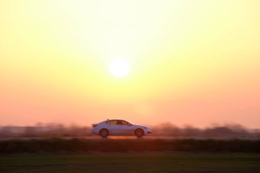 Gün batımında şehir içi yolda hızlı giden bir araba. Akşamları otoyol trafiği.