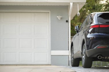 Car parked in front of wide garage double door on concrete driveway of new modern american house.