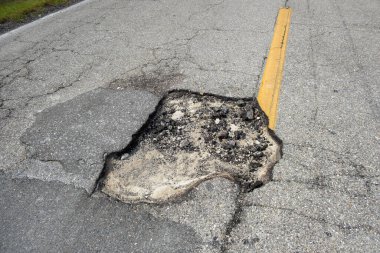 Hasarlı Amerikan yol yüzeyinde derin çukurlar var. Acilen tamir edilmesi gereken harabe bir sokak..