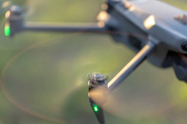 Drone quadcopter with digital camera and fast rotating propellers flying taking video and pictures.