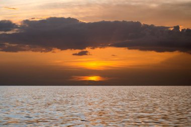 Okyanus batımı. Büyük beyaz güneş dramatik parlak gökyüzü arka planında, yumuşak akşam ufku denizin üstünde karanlık su üzerinde..