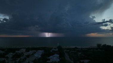 Ticari gemiler için fırtınalı bir gecede karanlık evleri ve okyanus kıyısında uzun deniz feneri olan deniz kenti. Deniz üzerinde şimşekler çakan fırtına gemiler için tehlike arz ediyor..