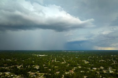 Landscape of dark ominous clouds forming on stormy sky during heavy thunderstorm over rural town area.
