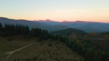 Gün batımında puslu tepeleri ve sisli vadisi olan güzel panoramik dağ manzarası.