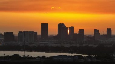 Ticari jet uçağı Florida, ABD şehir merkezindeki Tampa şehrinin şehir batımında havalanır. Modern Amerikan megapolis 'inde yüksek gökdelen binaları olan dramatik bir siluet..