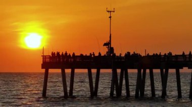 İnsanlar Florida 'daki Venice balıkçı iskelesinde gün batımının keyfini çıkarıyorlar. Deniz kenarında temiz hava alan yaz aktiviteleri.