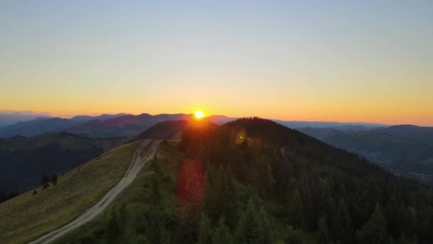 素晴らしい山の景色を眺める空想的な景色 野生の国立公園の高原で明るいカラフルな日没 黄色の設定日差しで照らされた丘の上のダークダートロード — ストック動画