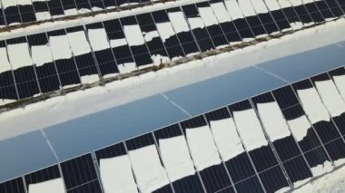 Aerial view of electrical power plant with solar panels covered with snow melting down in winter end for producing clean energy. Concept of low effectivity of renewable electricity in northern region.