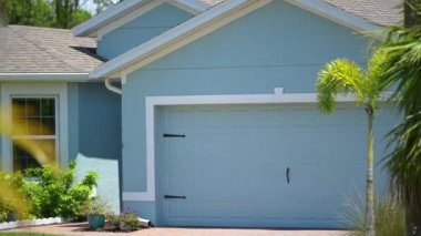 Florida 'daki tipik modern Amerikan özel evi çatısı asfalt kiremitlerle, geniş garaj kapısı ve bahçedeki yeşil çimlerle kaplı..