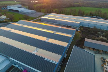 Sanayi binasının çatısına yeşil ekolojik elektrik üretmek için monte edilen mavi fotovoltaik güneş panellerinin hava görüntüsü. Sürdürülebilir enerji konsepti üretimi.