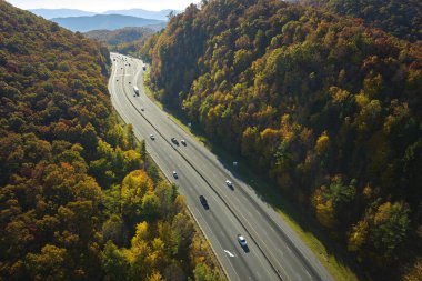 Aerial view of I-40 freeway in North Carolina leading to Asheville through Appalachian mountains in golden fall with fast moving trucks and cars. Interstate transportation concept.