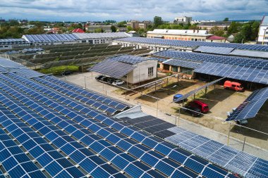 Sanayi binasının çatısına yeşil ekolojik elektrik üretmek için monte edilmiş mavi fotovoltaik panelli güneş enerjisi santralinin hava görüntüsü. Sürdürülebilir enerji konsepti üretimi.