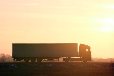 Kargo karavanı olan yarı kamyon akşam vakti otobanda mal taşır. Teslimat ulaşım ve lojistik kavramı.